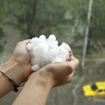 person holding handfuls of large hailstones