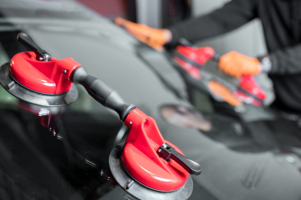 Auto technician using suction tools to install a new windshield during a professional windshield replacement service.